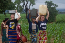 Ellen Mason, Alex White and Anja Wicker carry water from the well back to their hosts’ home.